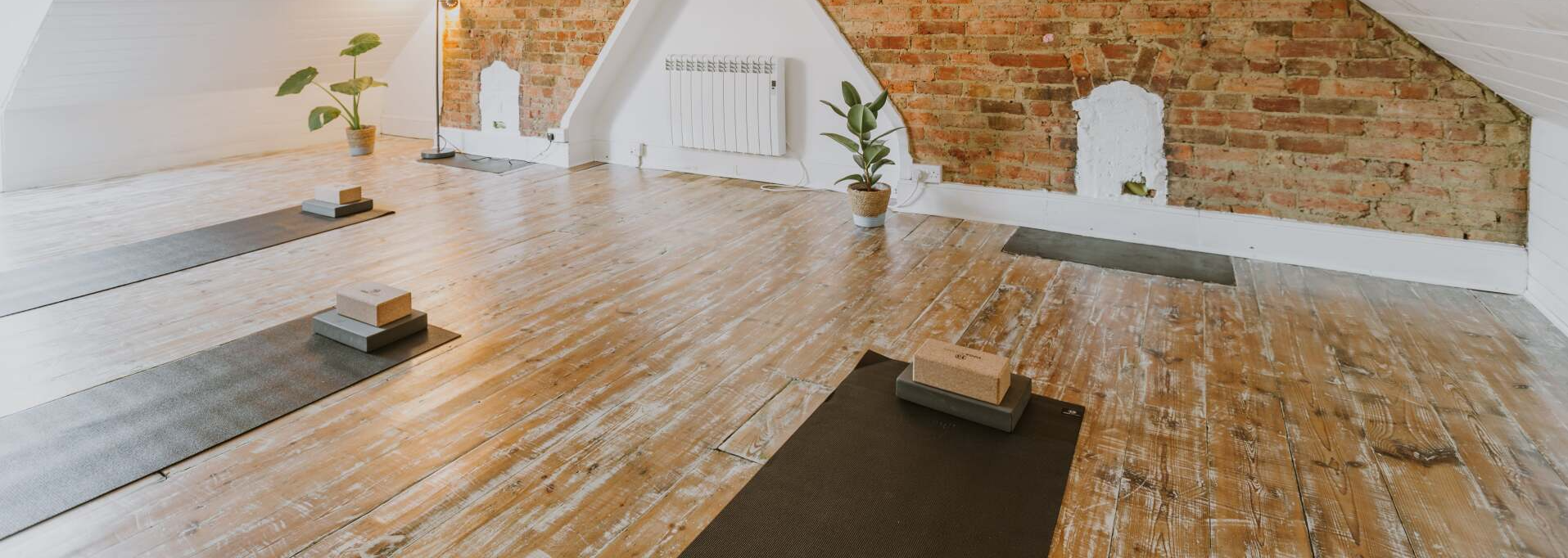 A loft studio with three Pilates mats laid out ready for a class