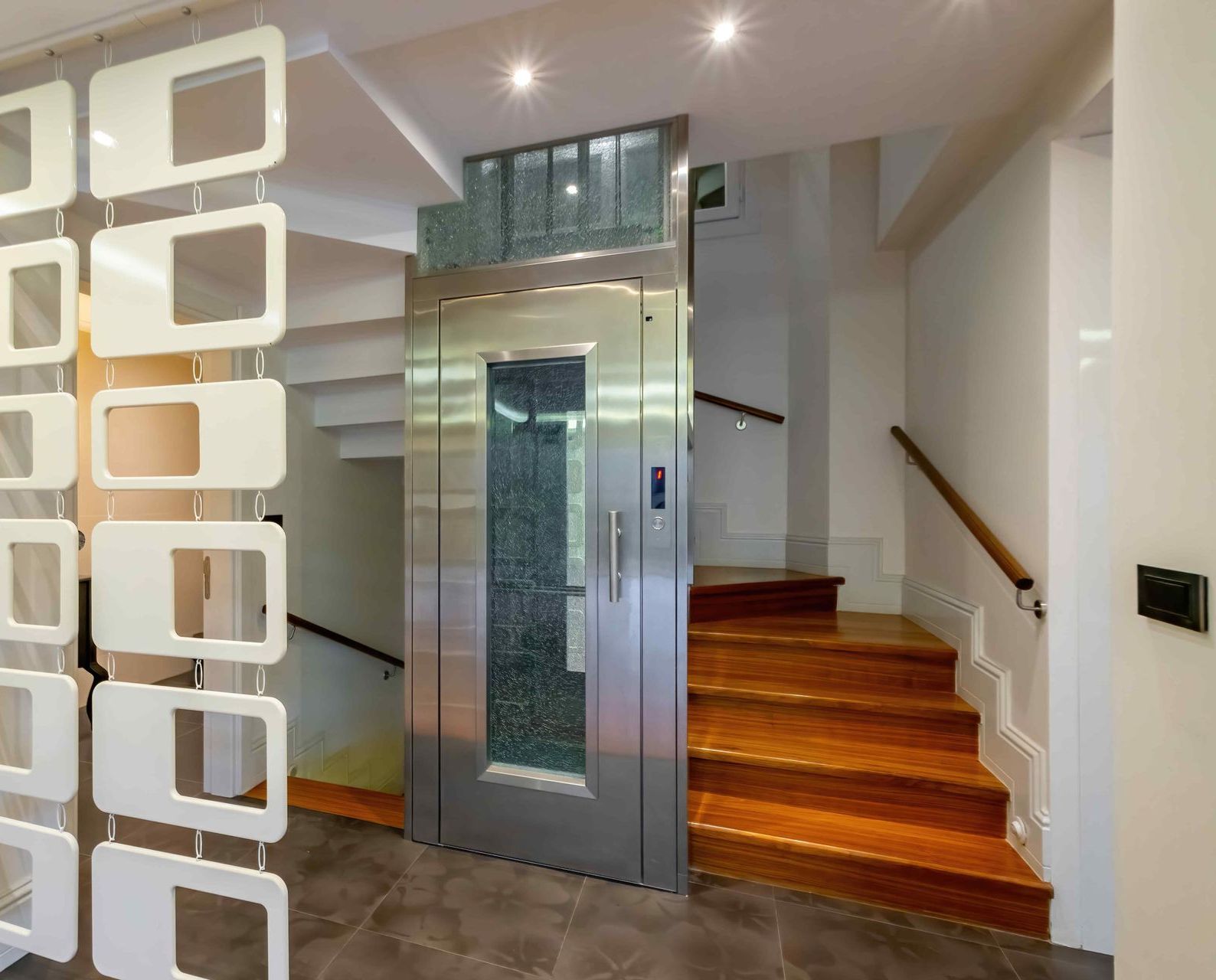 An elevator sets off the staircase area in a modern home.