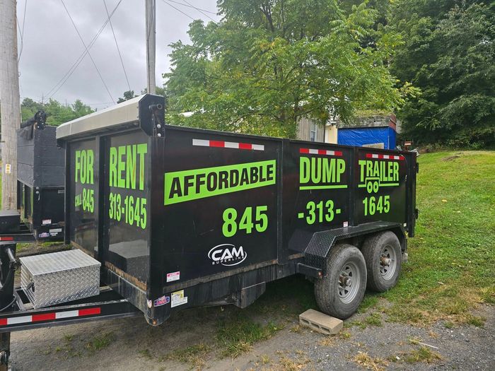 A dump trailer is parked in a grassy field.
