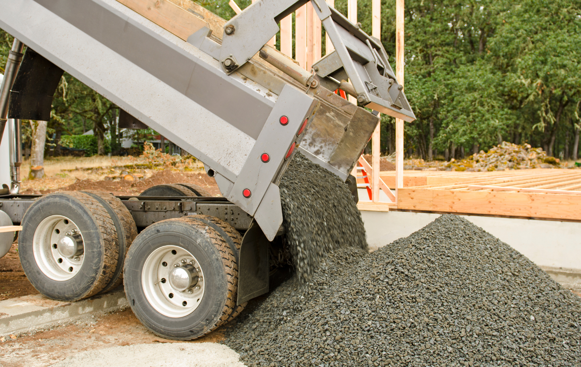 A dump truck is dumping gravel on a construction site.
