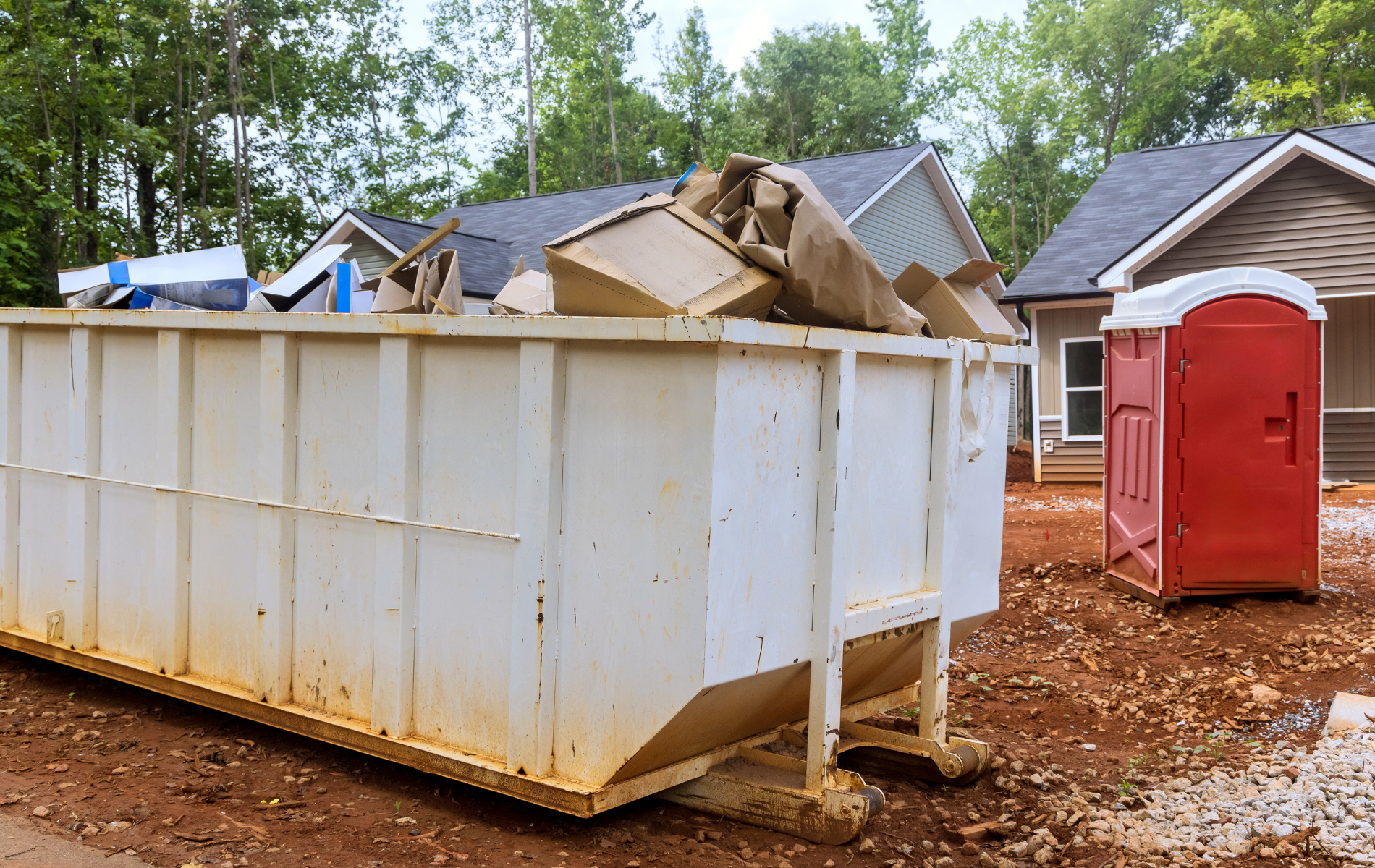 A large dumpster is sitting in front of a house under construction.