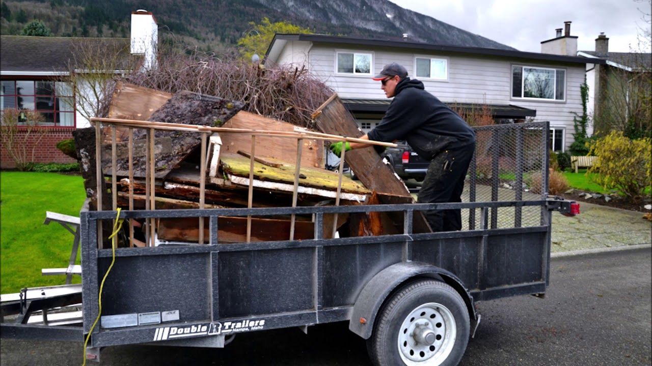 A man is pushing a trailer full of junk down a street.
