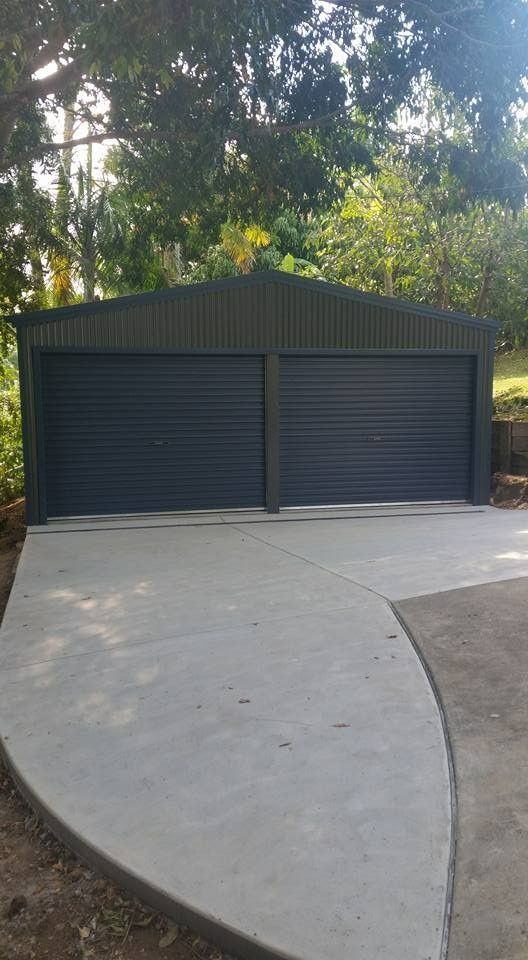 Dark Gray Two-car Garage With Roll-up Doors on a Concrete Driveway, Surrounded by Trees — North Coast Sheds & Garages in Casino, NSW