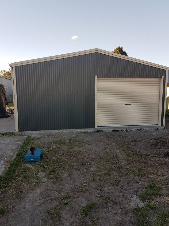 A Dark Gray Metal Shed With a Tan Garage Door, Set Against a Clear Sky — North Coast Sheds & Garages in The Northern Rivers, NSW