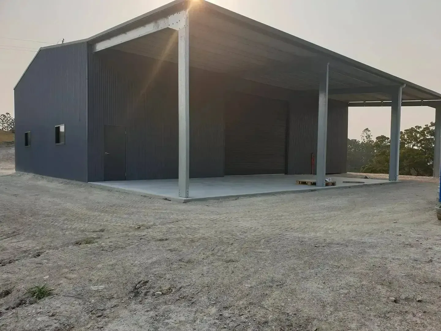 A Partially Constructed Gray Metal Building With a Concrete Floor, Set on Gravel in an Outdoor Setting — North Coast Sheds & Garages in Grafton, NSW