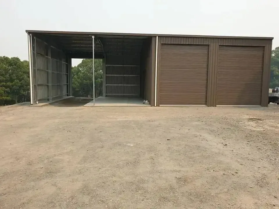 A Large Metal Shed With Open Sides and Two Enclosed Garage-style Doors, Sitting on a Gravel Lot — North Coast Sheds & Garages in Maclean, NSW
