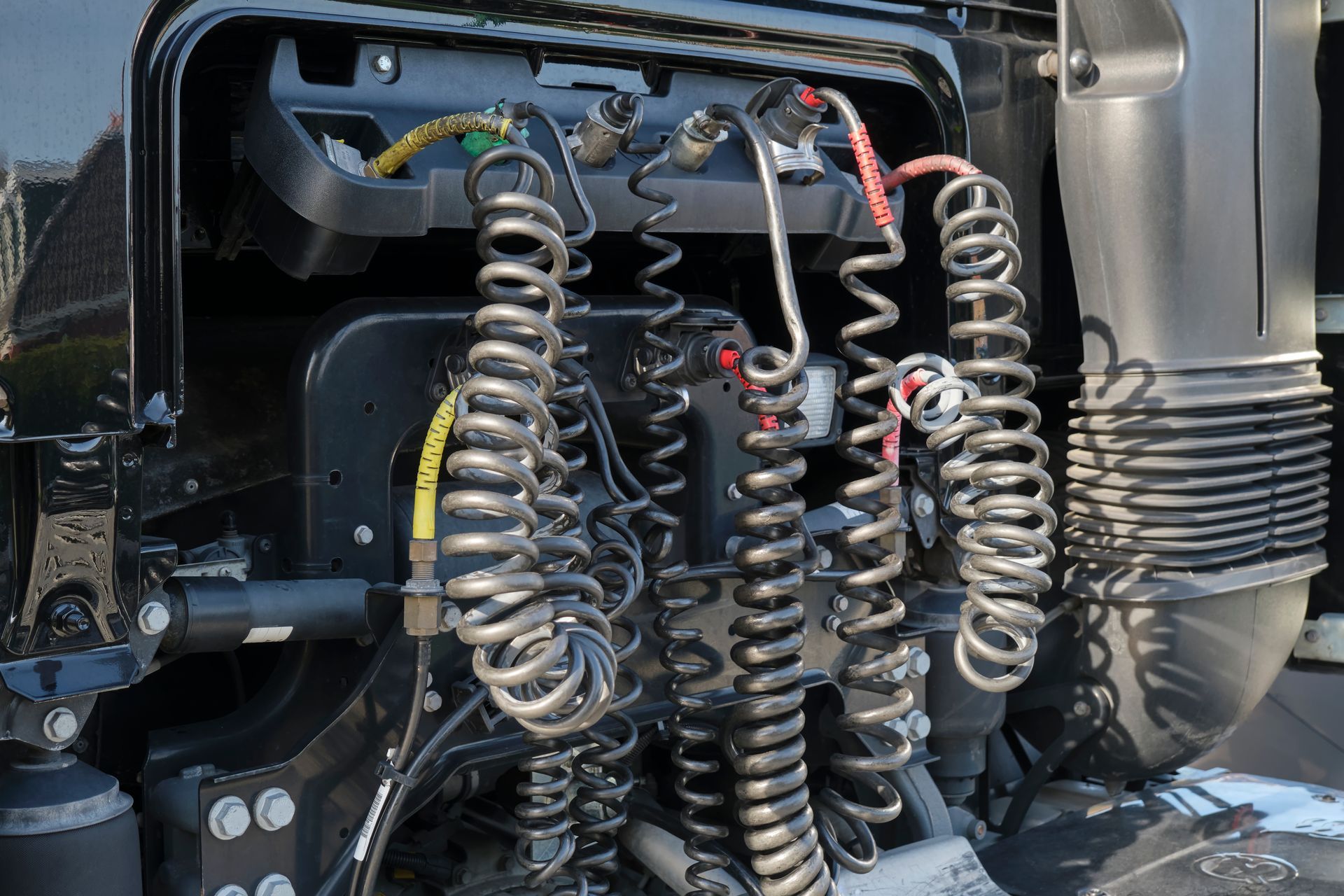 Pressure hoses, electrical wires and cables on a black truck for coupling with a trailer.