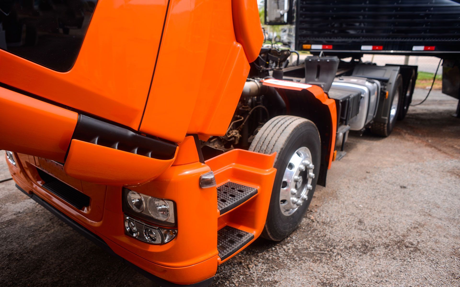 Close-up of an orange semi-truck cab connected to a black trailer.