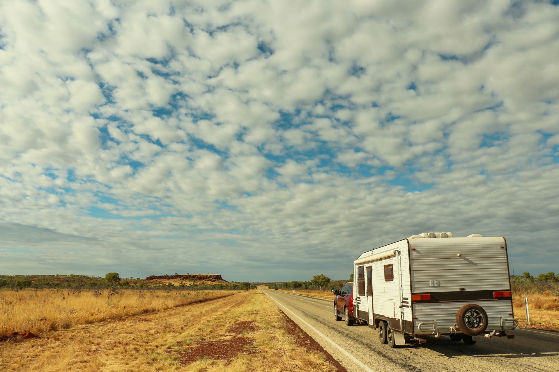 Car towing a caravan on a rural road, illustrating safe travel with brake controllers.
