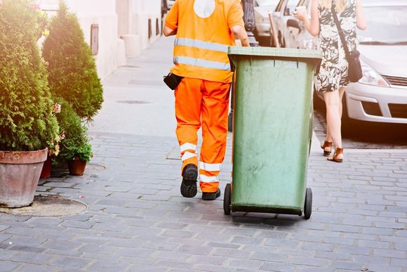 operaio durante il trasporto di un contenitore con rifiuti