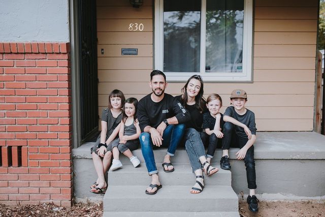 Debbie & Gabriel Mayes sit on their porch for a family portrait with their 4 children as an example of a minimalist lifestyle: 6 things you need to know.