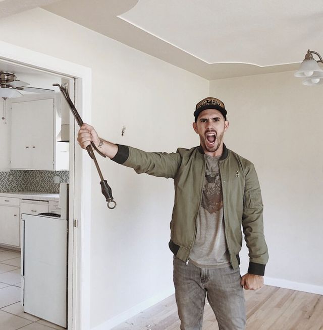 Gabriel Mayes of The Mayes Team holds demolition tools in his right hand as he makes a pretend angry face in preparation for home remodeling.