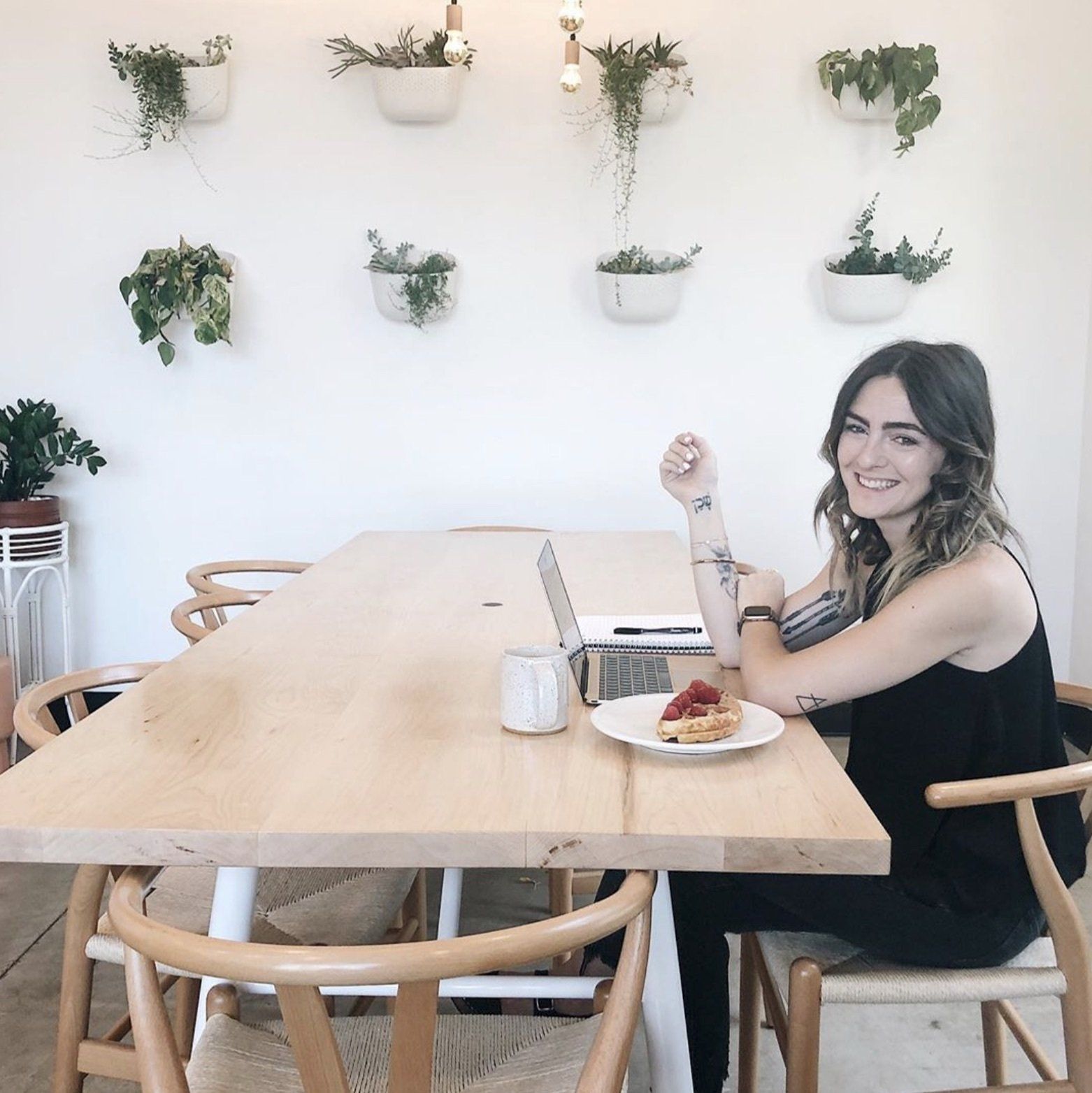 Debbie Mayes smiles about finding her Instagram niche while sitting at a table with her laptop and raspberry topped waffles.