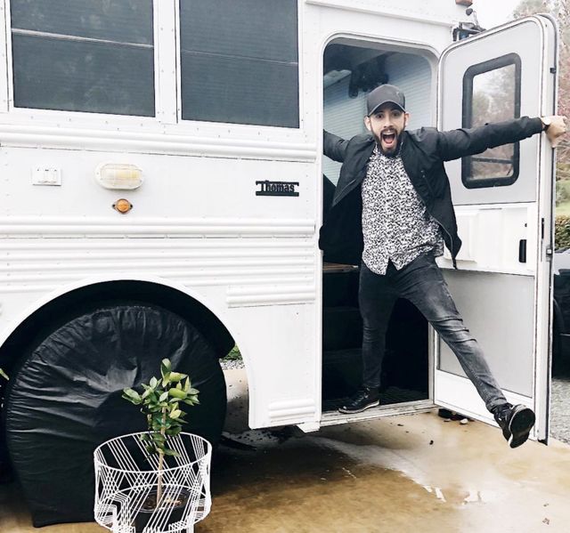 Gabriel Mayes jumps out of the skoolie bus as he celebrates how to make money on the road when living on a skoolie.