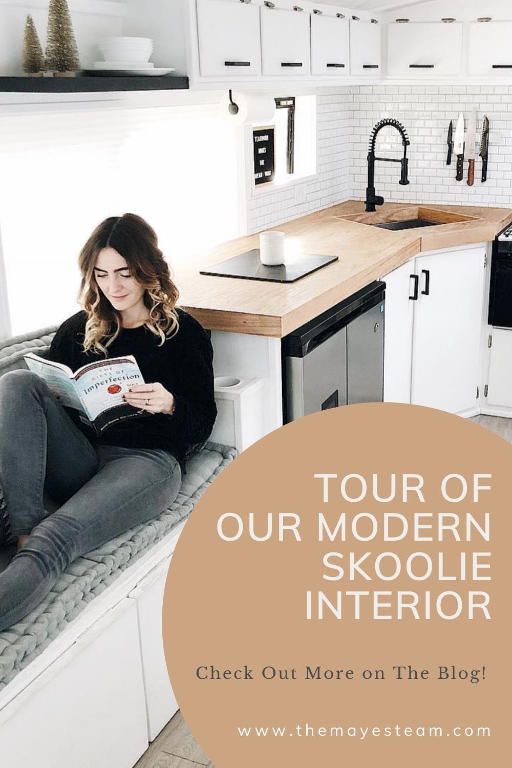 Debbie Mayes sits in the Skoolie kitchen reading a book. Image overlaid with text that reads Tour of Our Modern Skoolie Interior Check out More on The Blog!