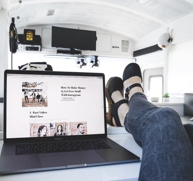 Debbie Mayes sets her feet next to her laptop as she rests in the skoolie bus planning how to traffic hack your competition.