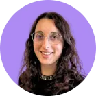 Une femme portant des lunettes sourit à la caméra sur un fond violet.