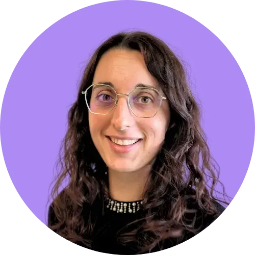 Une femme portant des lunettes sourit à la caméra sur un fond violet.