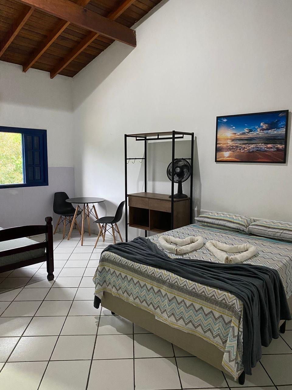 Um quarto com uma cama, cadeiras, uma mesa e um ventilador. Pousada Meraki
