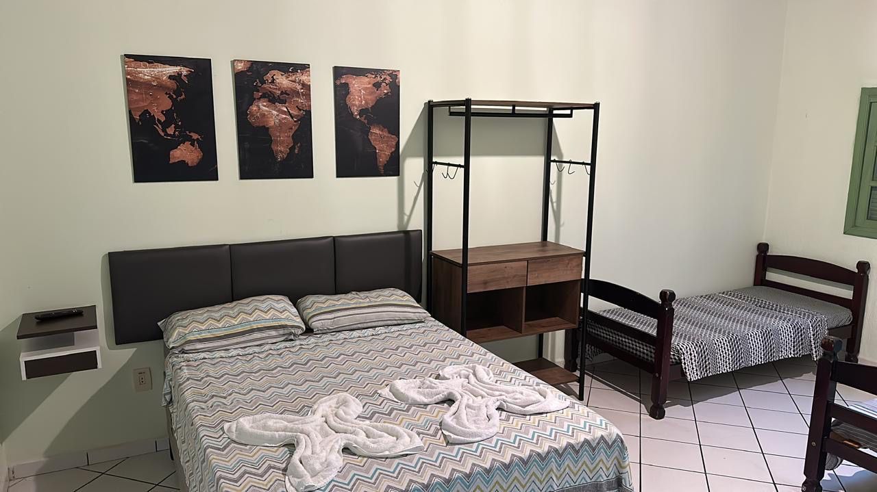 Um quarto com uma cama, duas camas, uma cômoda e um mapa do mundo na parede. Pousada Meraki