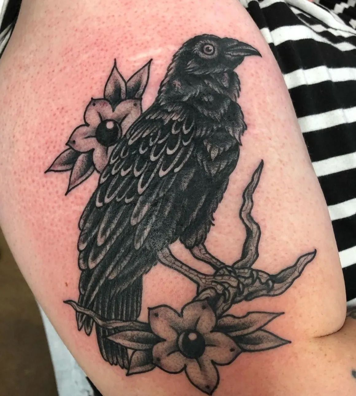 A black bird is sitting on a branch with flowers