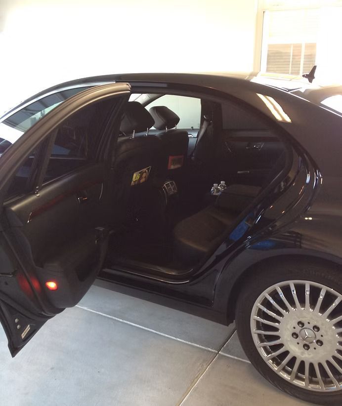 Black sedan with the rear door open, revealing leather seats, in a garage.