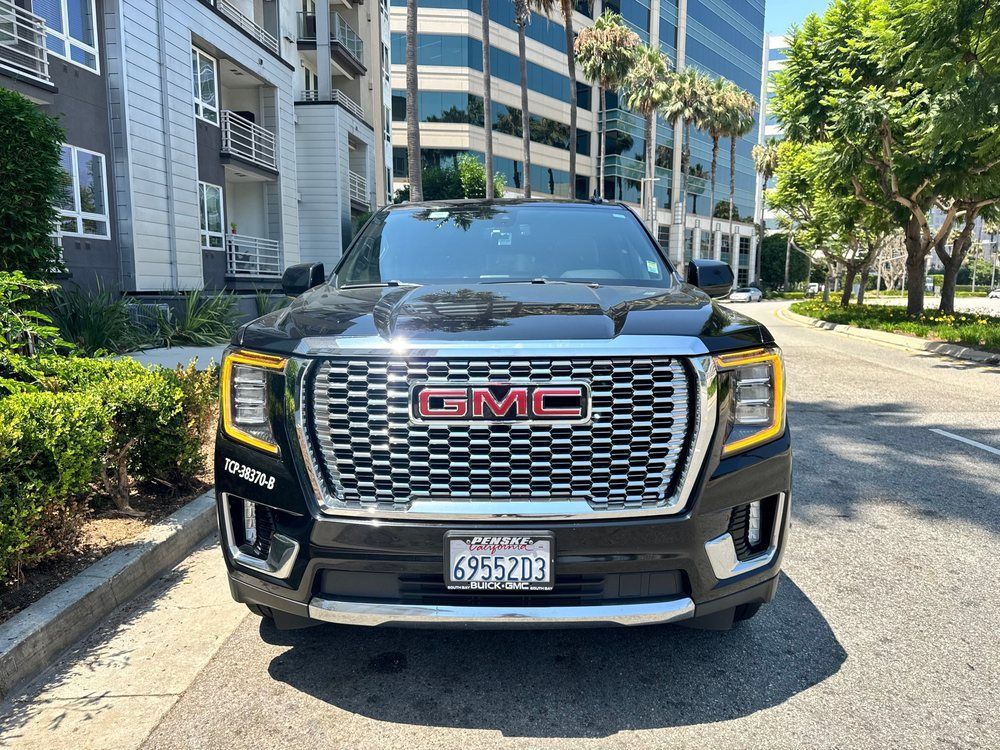 Black GMC Yukon SUV parked on a city street, front view. California license plate visible.