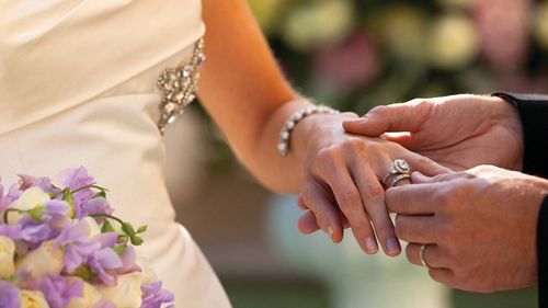 Man placing a wedding ring on a woman's finger during a wedding ceremony.