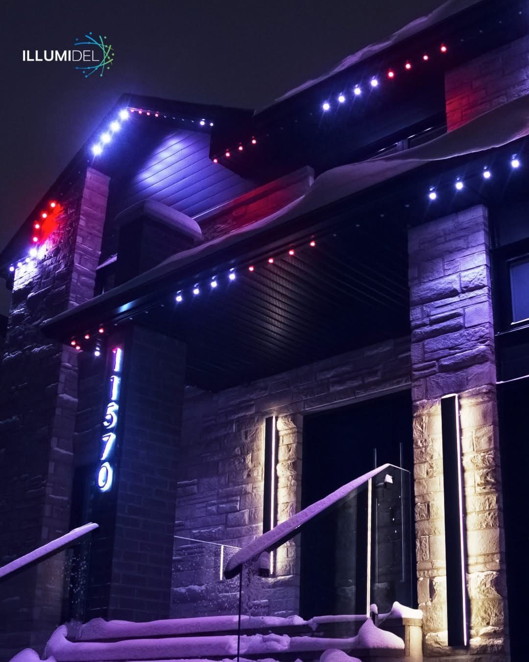 House with purple and red Christmas lights, illuminated address, and snow-covered roof.
