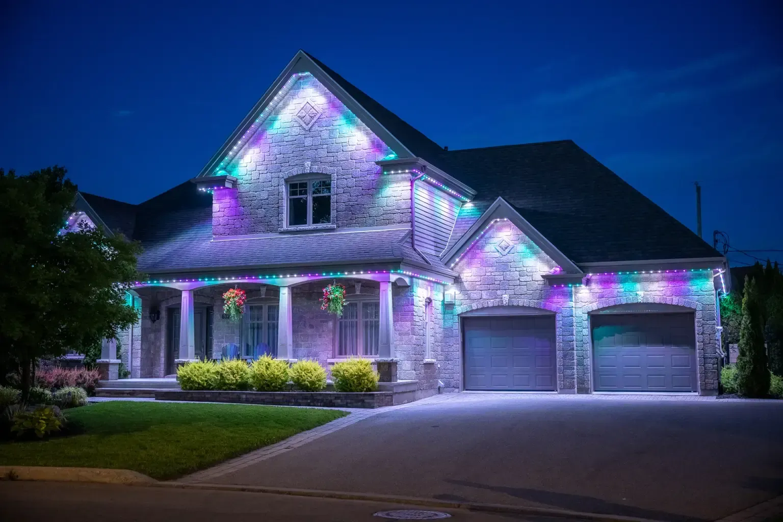 House with colorful, glowing lights decorating the roofline, windows, and garage doors at dusk.
