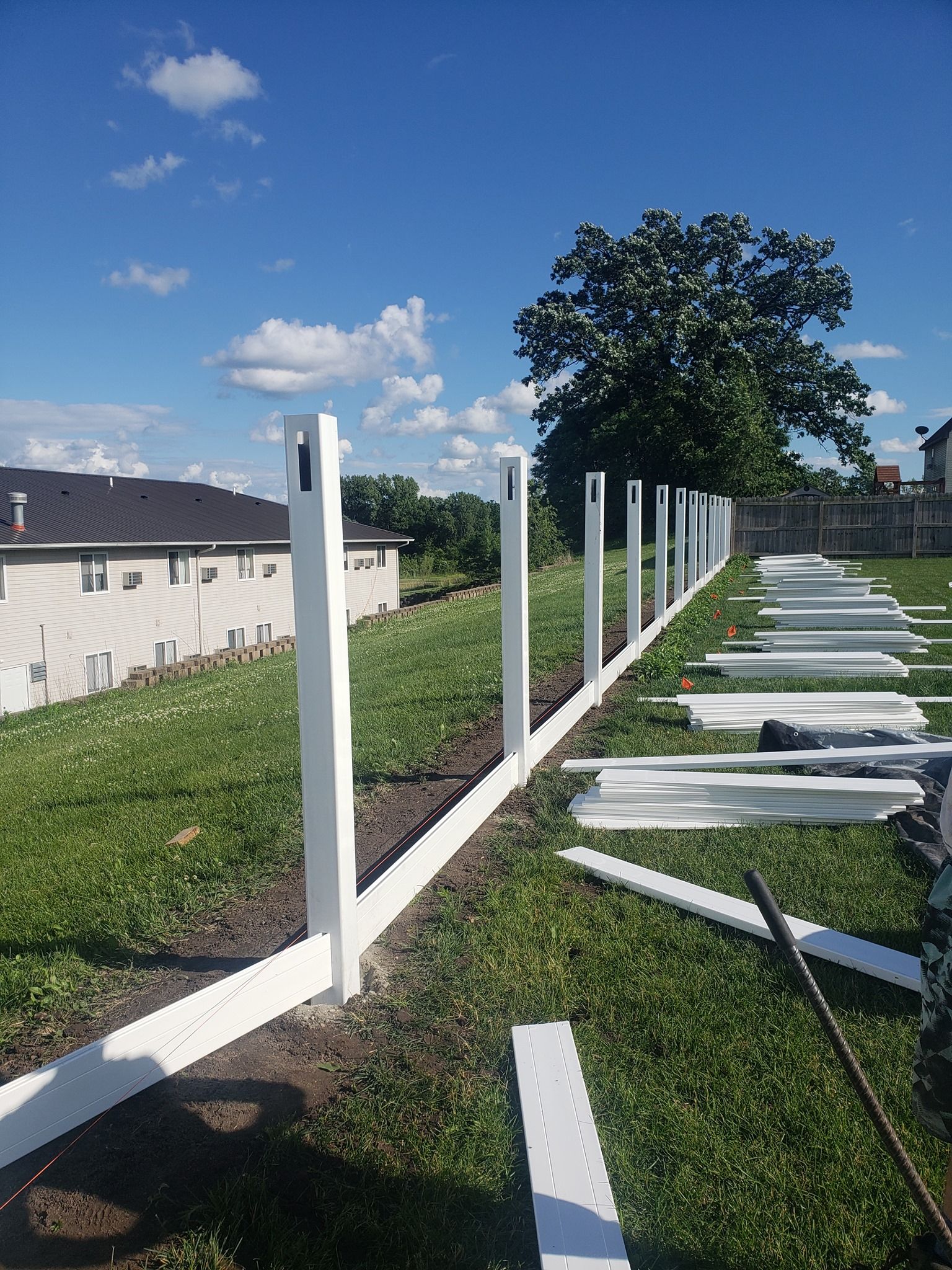 A white fence is being built in a backyard.