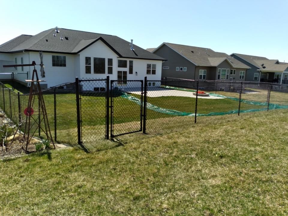 A backyard with a chain link fence and a house in the background.