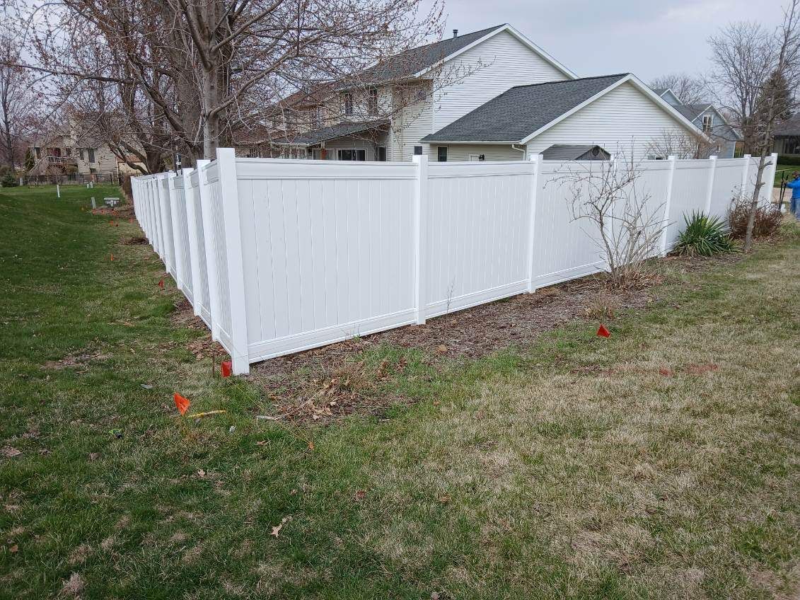 A white fence is in the backyard of a house.