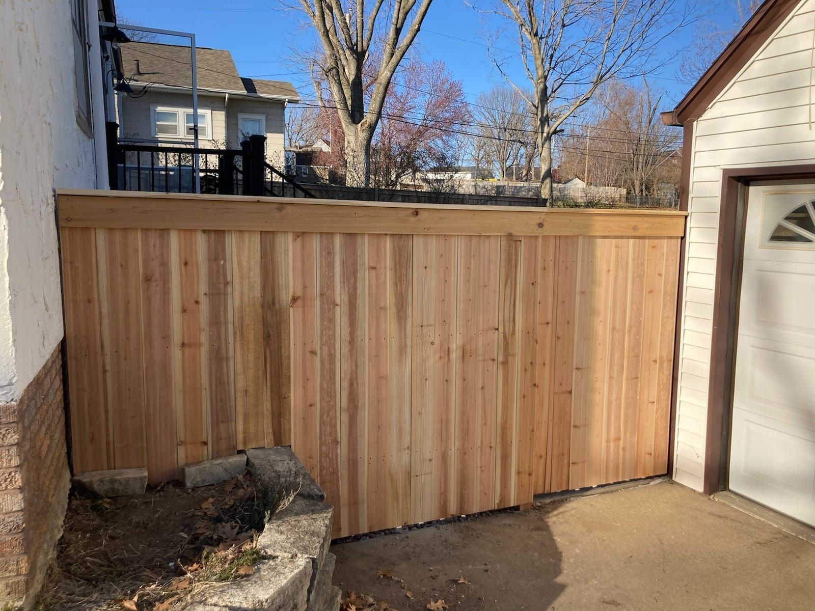 A wooden fence is sitting next to a garage door.