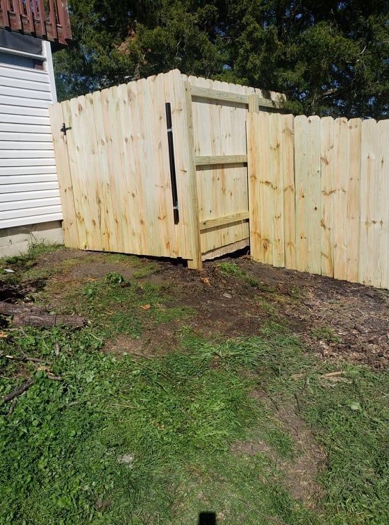 A wooden fence with a gate in the backyard of a house.