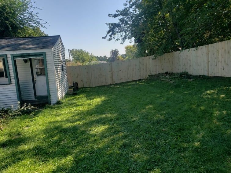 A backyard with a shed and a wooden fence.