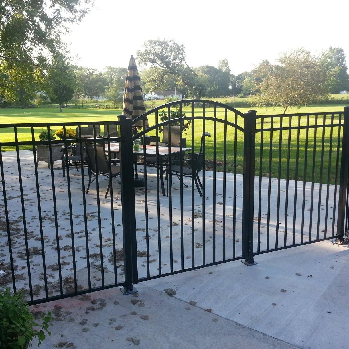 A black fence surrounds a patio with a table and chairs