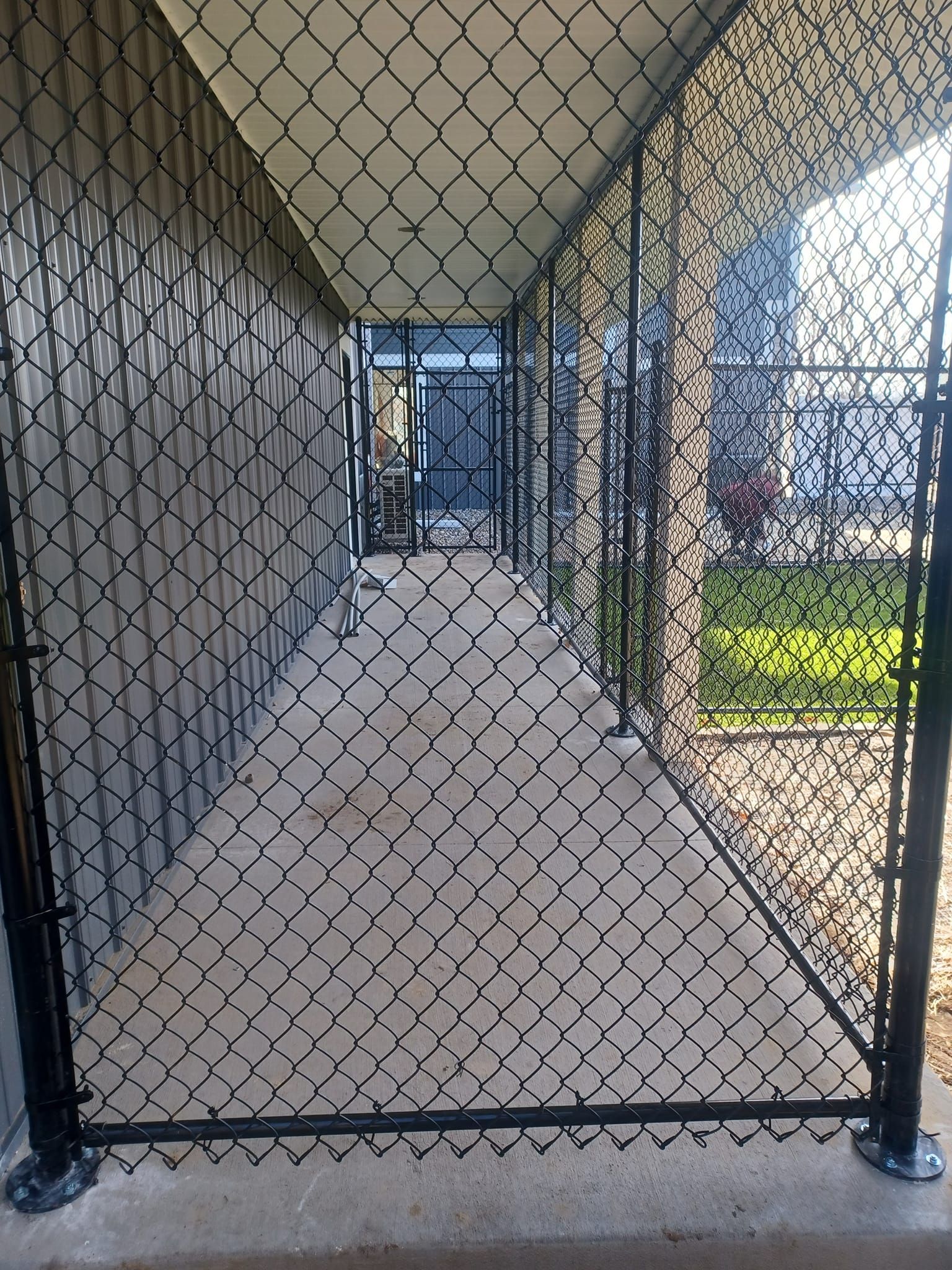 A chain link fence surrounds a walkway leading to a building
