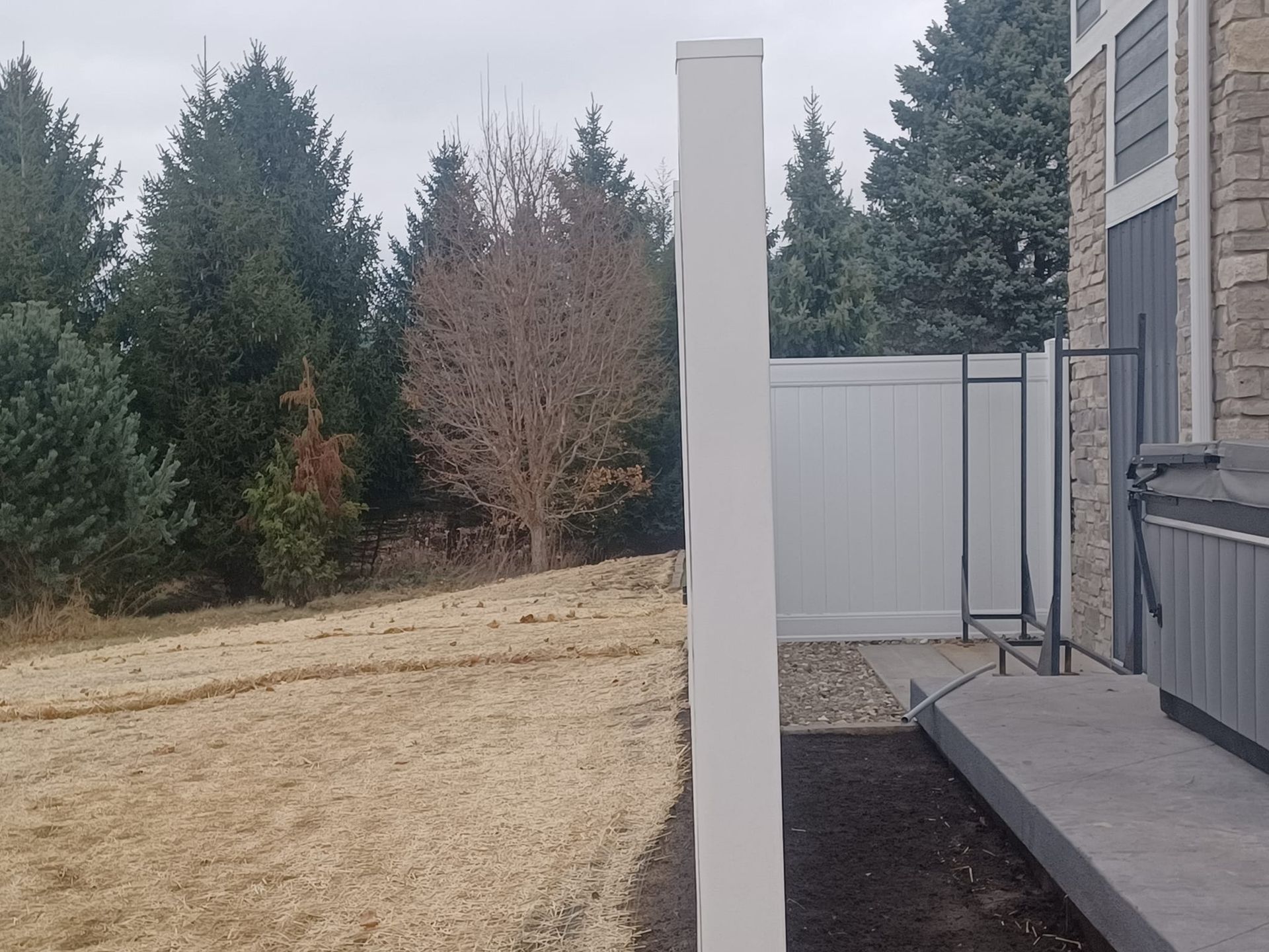 A white fence surrounds a grassy field in front of a house.