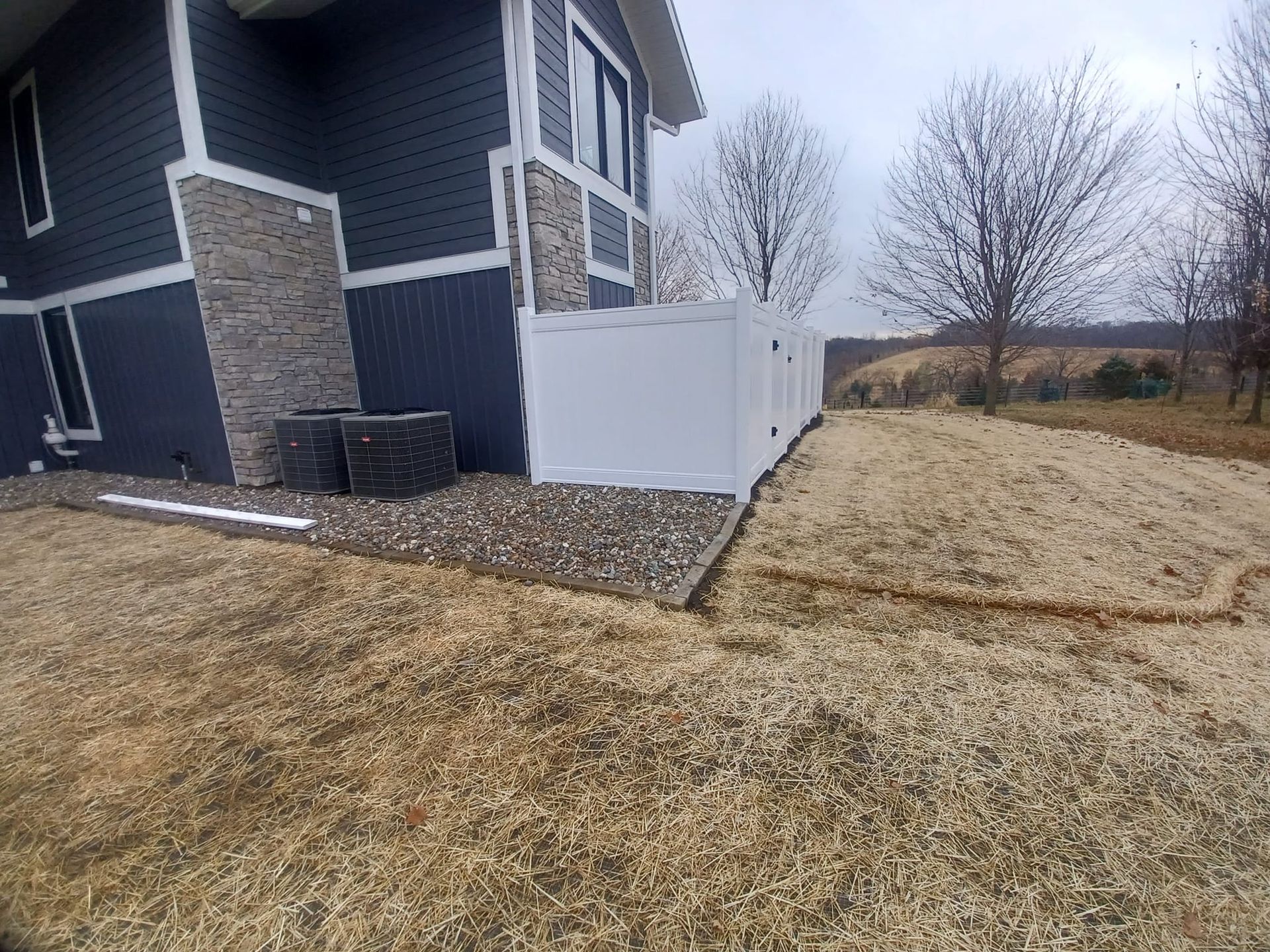 A blue house with a white fence in front of it.