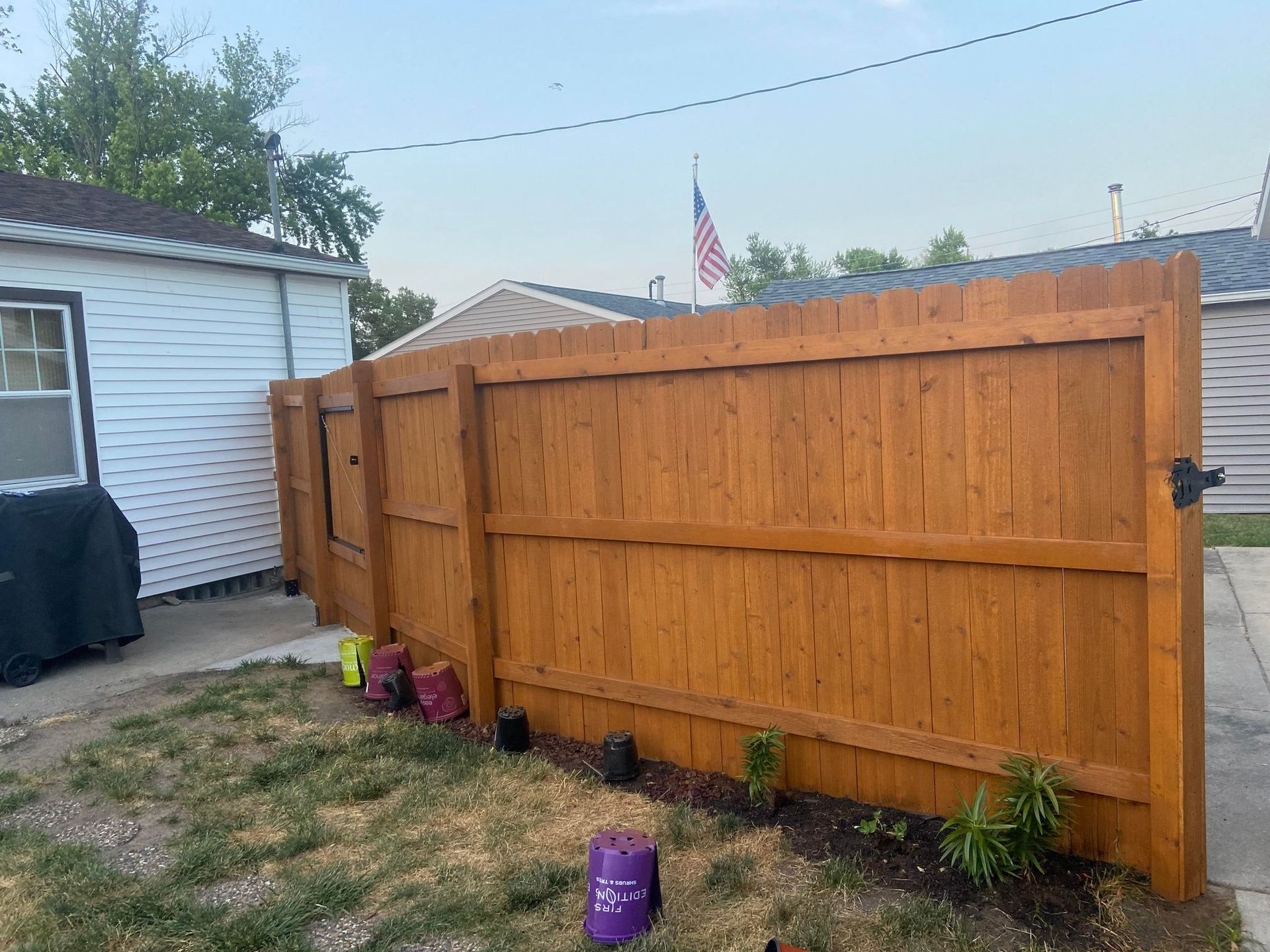 A wooden fence is in the backyard of a house.