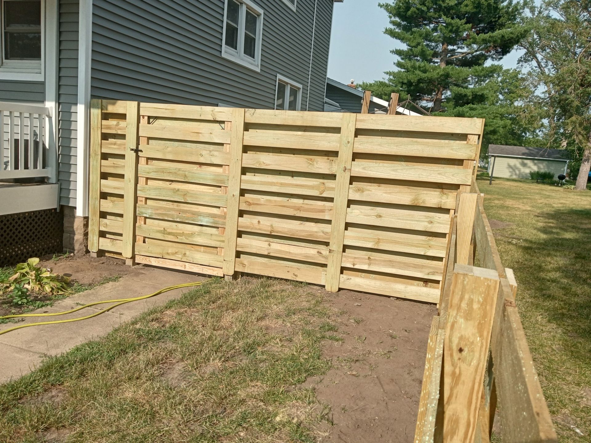 A wooden fence is being built in front of a house.