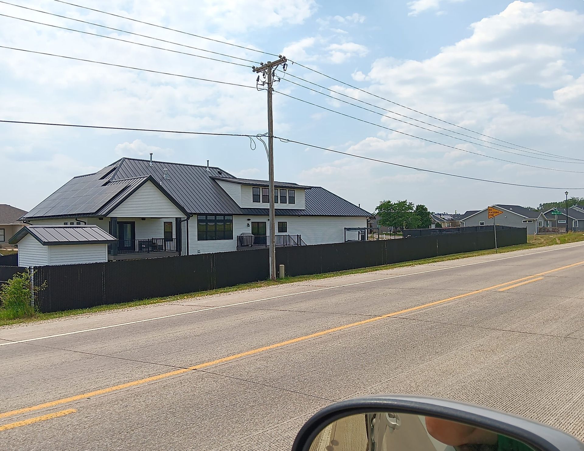 A house with a black fence is on the side of the road