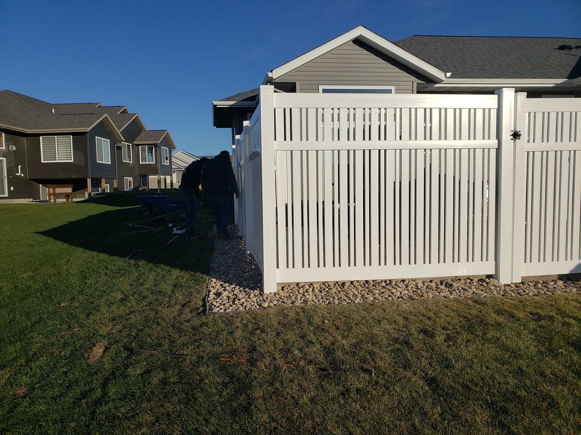 A white fence is in front of a house in a residential area.