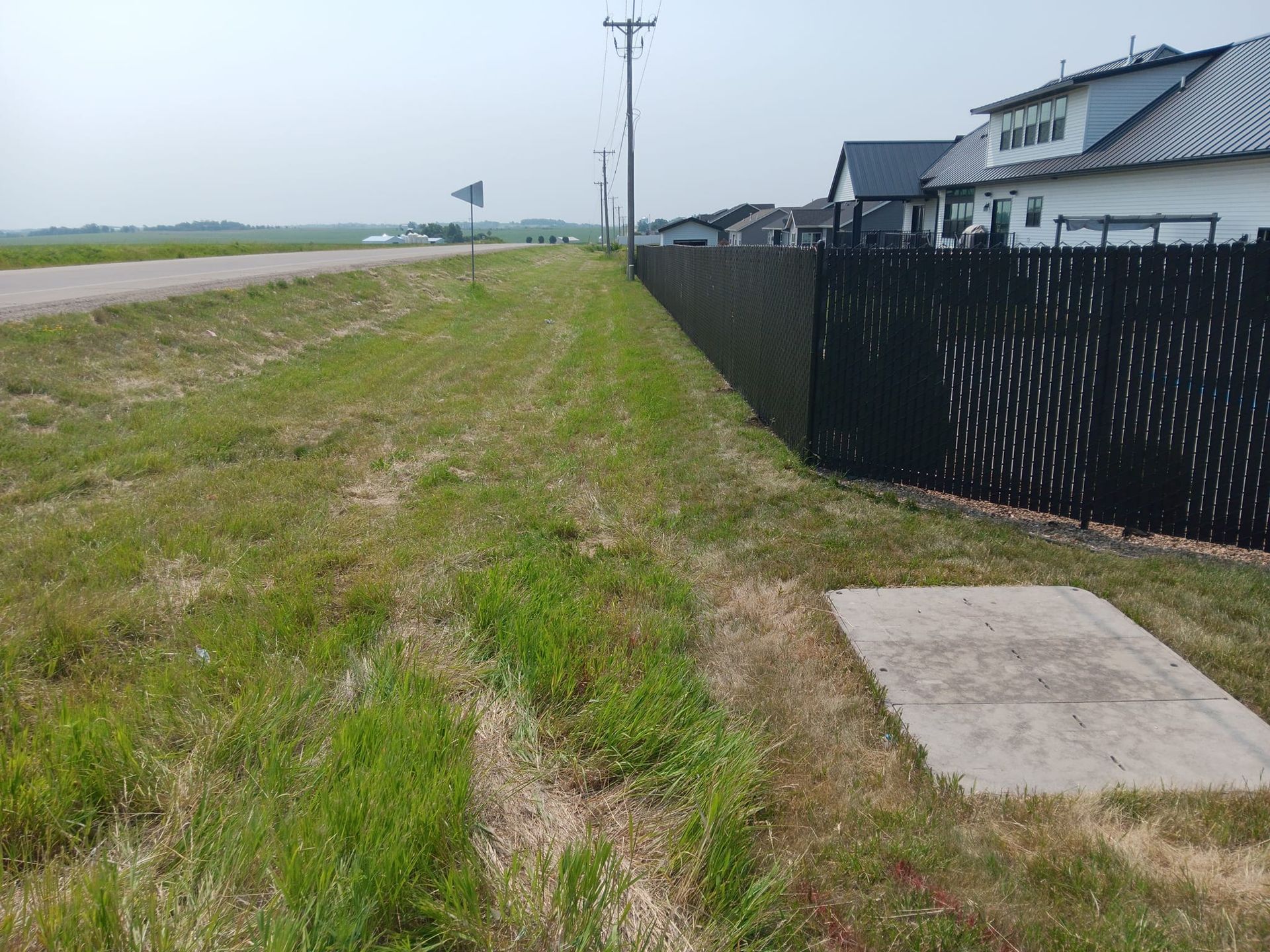A black fence surrounds a grassy field next to a road