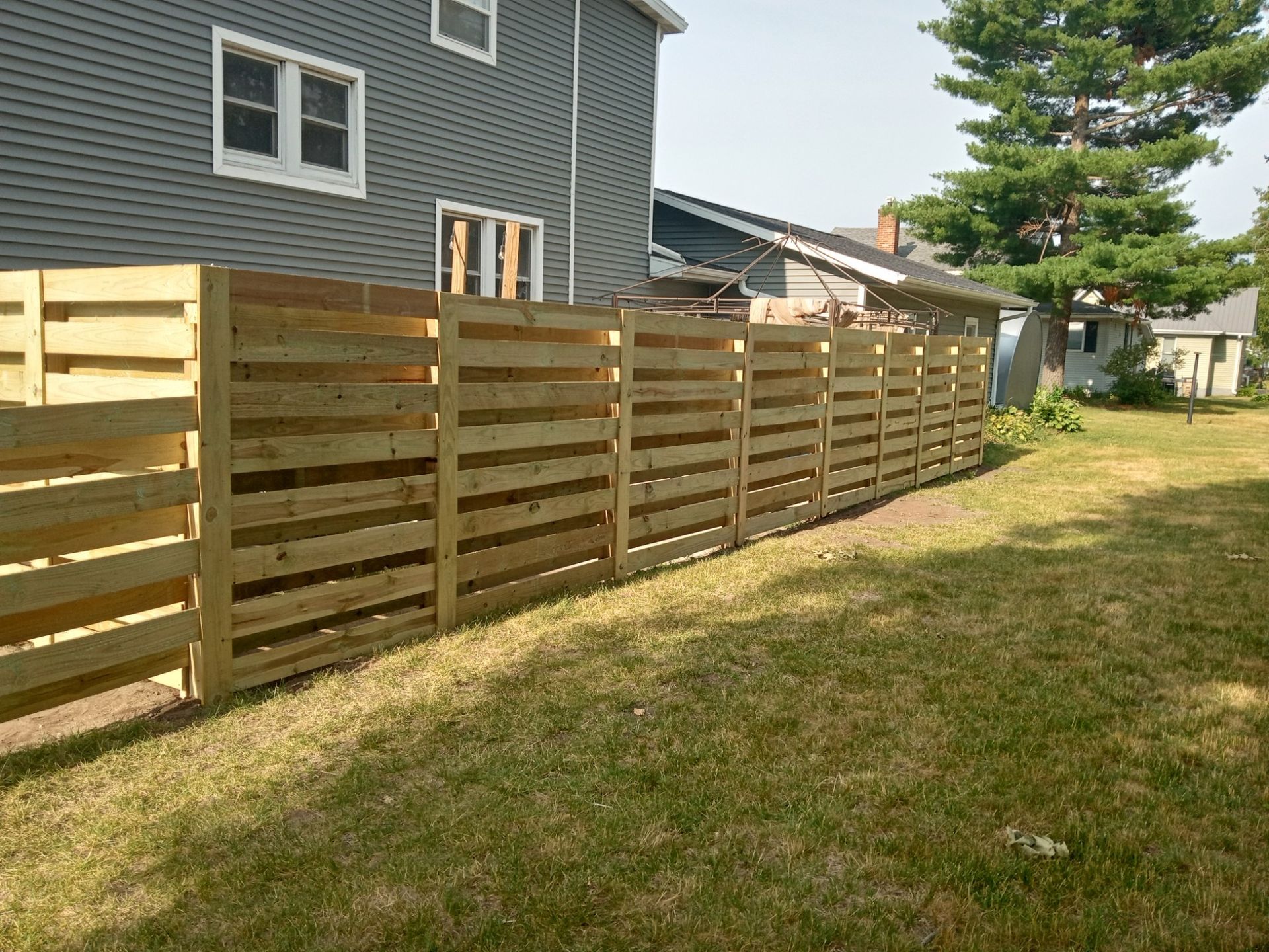 A wooden fence is in the backyard of a house.