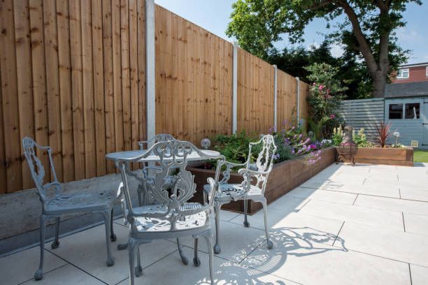 A patio with a table and chairs in front of a wooden fence.