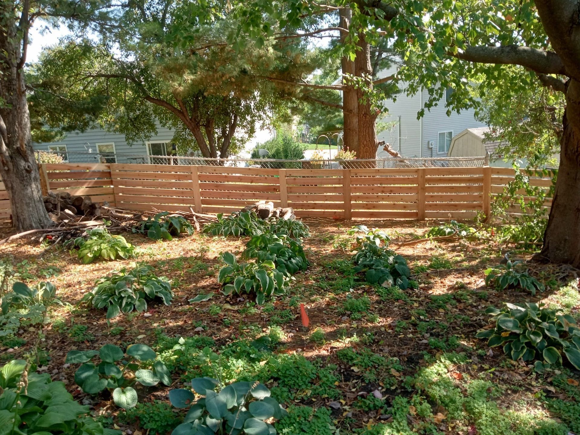 A wooden fence surrounds a lush green yard.