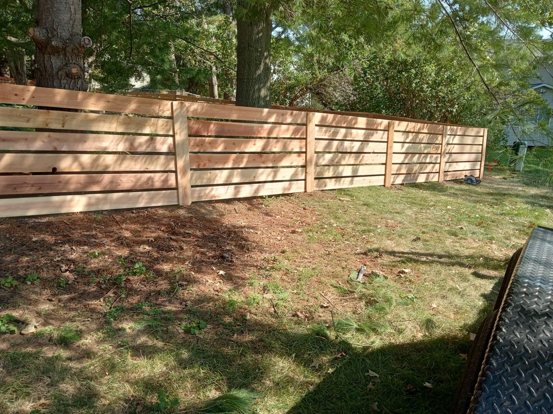 A wooden fence is sitting in the middle of a lush green yard.