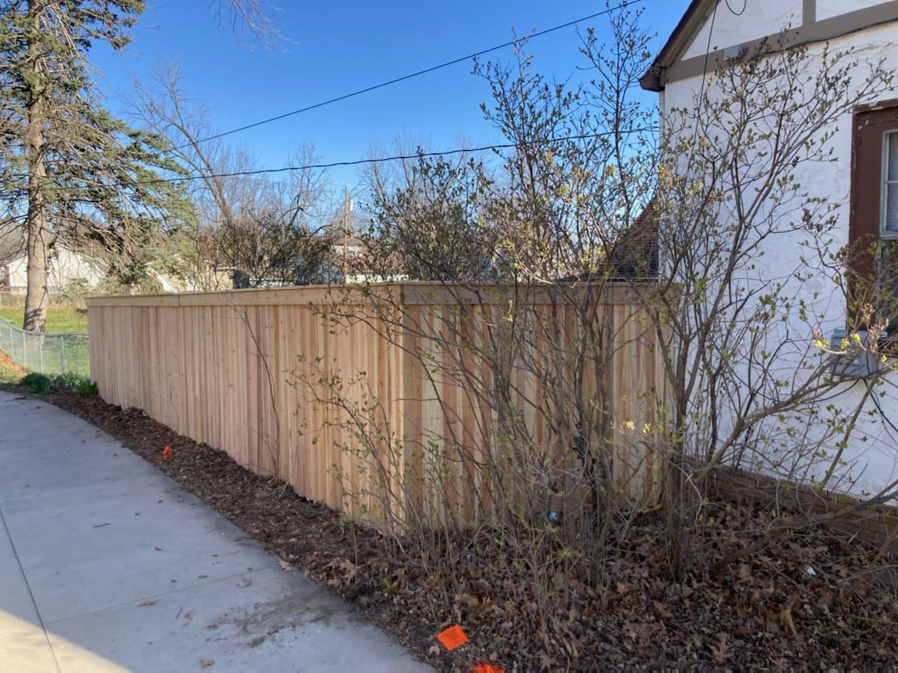 A wooden fence is sitting next to a white house.